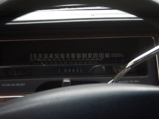 Dashboard gauges and steering wheel in a car. Shows speedometer up to 140 mph and 'R N D 2' gear indicator