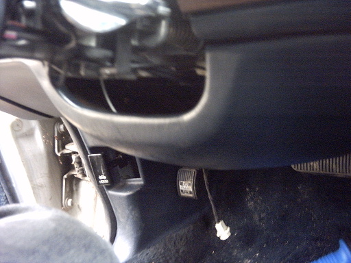 Car interior showing pedals, hood release lever, and part of the dashboard