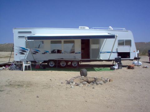 2004 Ford F-150 - A travel trailer is set up in an outdoor, sandy location under a clear blue sky.