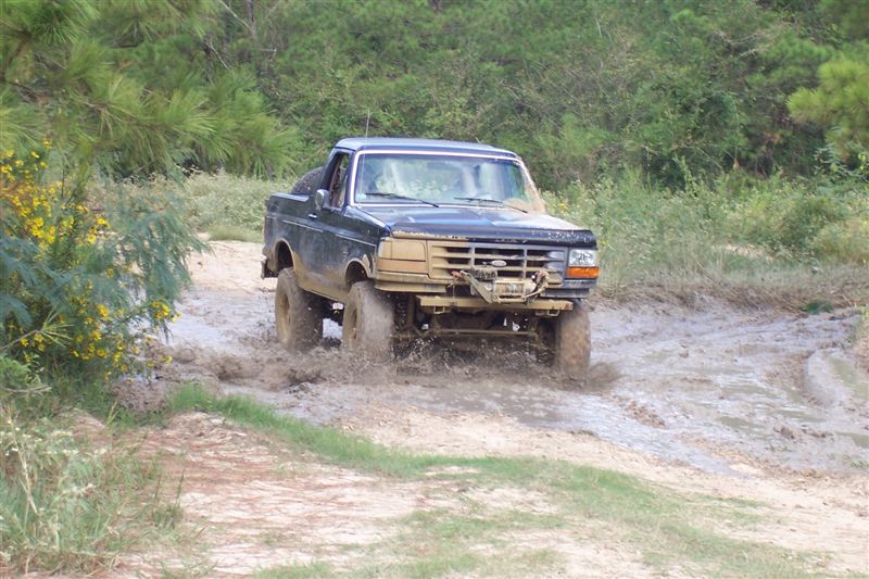 Black Ford F-Series truck driving through mud. It has a winch on the front bumper