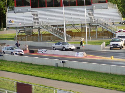 1998 Ford Taurus - A silver sedan is positioned on a drag strip, with a white pickup truck visible in the background.