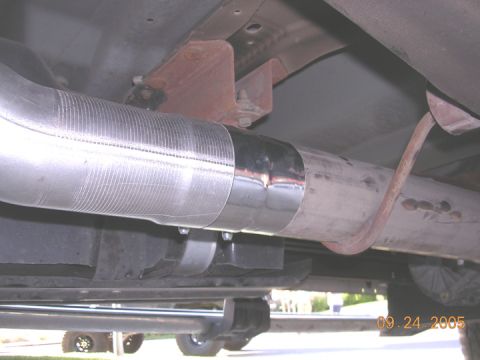 2004 Ford F-250 - Exhaust pipe repair using a metal sleeve and clamp, viewed from underneath the vehicle.