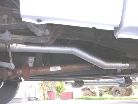 2004 Ford F-250 - The photo shows the exhaust system and driveshaft of a truck, with another vehicle in the background.