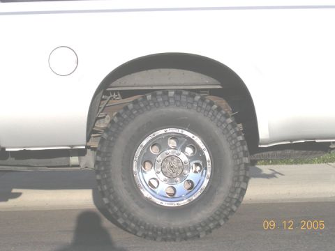 2004 Ford F-250 - A close-up shot focuses on the rear wheel and fender of a white pickup truck.