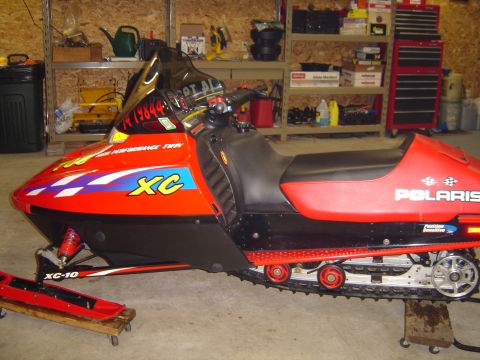 1978 Ford Bronco - A red and black Polaris snowmobile with XC graphics is parked indoors.