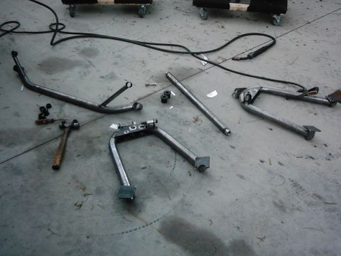1978 Ford Bronco - Various motorcycle kickstand components and tools are arranged on a workshop floor.