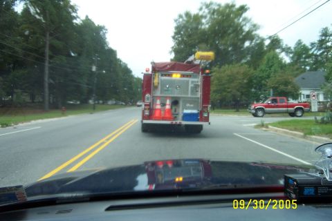 1998 Ford Crown Victoria - A fire truck is seen from behind on a road, with a red pickup truck in the background at an intersection.