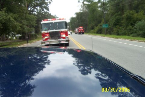 1998 Ford Crown Victoria - A fire truck is seen driving on a road, with another fire truck in the distance, as viewed from a blue car.