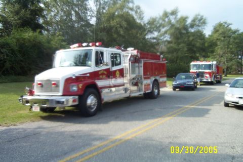 1998 Ford Crown Victoria - Three-quarter front view of a red and white Freightliner FL-series fire engine with a department seal on the cab door, roof lightbar and ch…