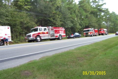 1998 Ford Crown Victoria - Emergency vehicles are lined up on the side of a road on a cloudy day.