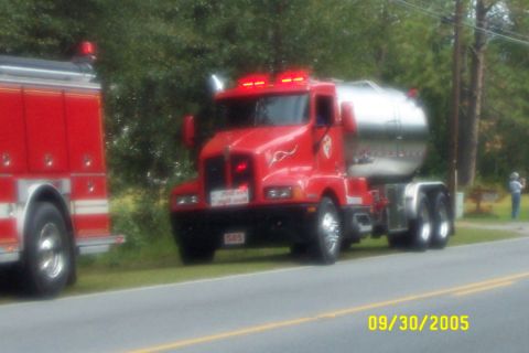1998 Ford Crown Victoria - Two emergency vehicles, a tanker truck and a fire truck, are parked on the side of the road.