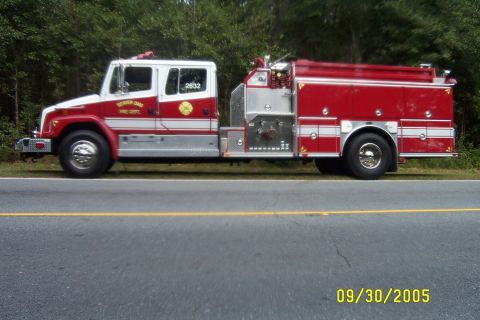 1998 Ford Crown Victoria - A red and white fire truck is parked on the side of a road with trees in the background. The date 09/30/2005 is visible.