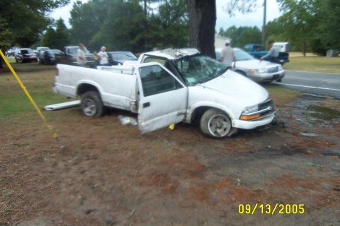 1998 Ford Crown Victoria - A damaged white pickup truck sits off the side of the road with other vehicles visible in the background.