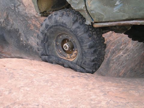 1993 Ford Bronco - Flat tire on an off-road vehicle navigating rocky terrain.