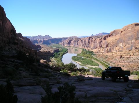 1993 Ford Bronco - A black pickup truck is parked on a rocky overlook, with a wide canyon and river stretching into the distance under a clear blue sky.
