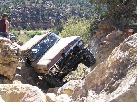 1993 Ford Bronco - This modified SUV is attempting to climb a steep, rocky trail with significant articulation.