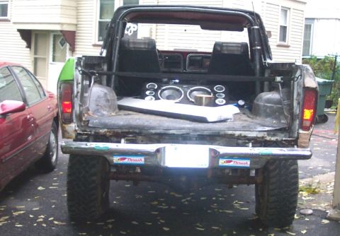1978 Ford Bronco - Rear view of a 1978 Ford Bronco with aftermarket speakers installed in the bed, parked next to a red car.