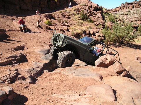 1993 Ford Bronco - An off-road vehicle tackles a challenging rocky trail in a desert landscape.