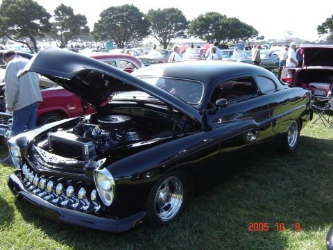 1993 Ford Bronco - A customized black coupe is displayed with its hood open at a car show, surrounded by other vehicles.