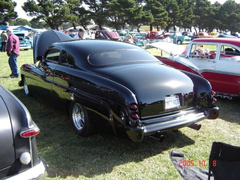 1993 Ford Bronco - A black coupe with custom wheels and lowered suspension is parked on grass at an outdoor car show.