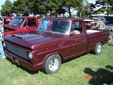 1993 Ford Bronco - A custom pickup truck is displayed at an outdoor event, with other vehicles visible in the background.