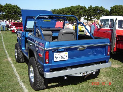 1993 Ford Bronco - A blue Ford Bronco with its hood up is parked on grass next to a red and white vehicle.