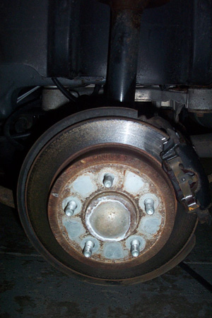 1999 Chrysler 300M - Close-up of a rusty rear disk brake assembly, showing the rotor and caliper.