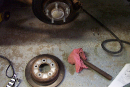 1999 Chrysler 300M - Close-up of a car's brake rotor and caliper, with a pink rag nearby.