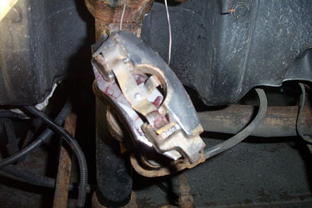 1999 Chrysler 300M - Close-up of a disk brake caliper, showing wear and a SuperMotors watermark.