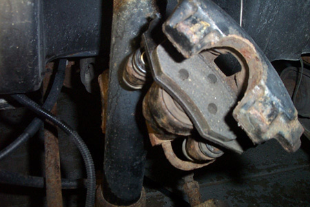 1999 Chrysler 300M - Worn brake caliper and rotor assembly, likely needing replacement.