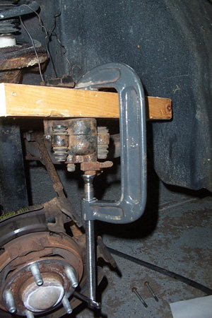 1999 Chrysler 300M - A C-clamp and wooden block are used to compress a brake caliper.