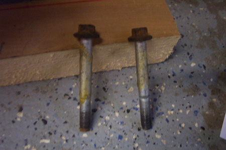 1999 Chrysler 300M - Two bolts, likely for disk brakes, are shown on a wooden plank.