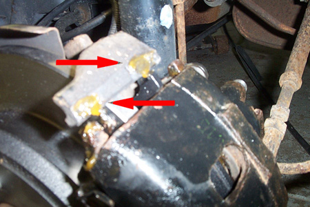 1999 Chrysler 300M - Close-up of a vehicle's disk brake caliper, showing yellow grease on the caliper bracket.