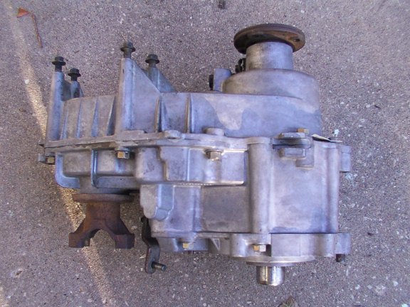 Aluminum transfer case removed from vehicle, sitting on concrete pavement