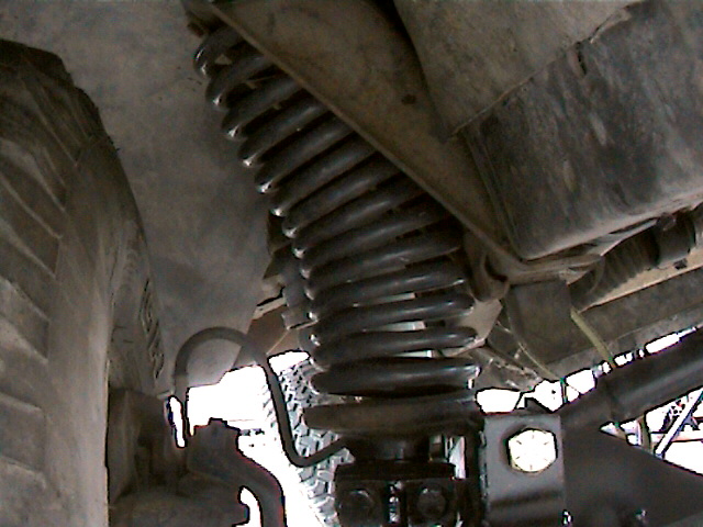 Underside view of a coil spring, axle and shock on a truck front suspension