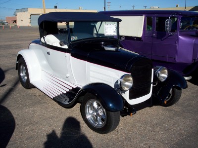 1972 Ford Ranchero - A two-tone convertible hot rod is parked outdoors next to a large purple truck.