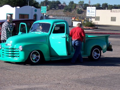 1972 Ford Ranchero - A teal pickup truck is parked outside with its doors open, and a man is entering the driver's side.