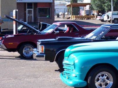 1972 Ford Ranchero - A line of classic vehicles, including a red 1972 Ford Ranchero, are displayed at an outdoor event.
