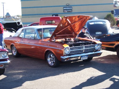 1972 Ford Ranchero - A classic orange coupe is displayed with its hood up at an outdoor event, surrounded by other vehicles.