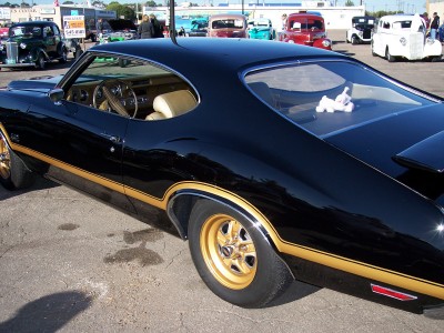 1972 Ford Ranchero - A classic black muscle car with gold accents is parked outdoors among other vehicles.