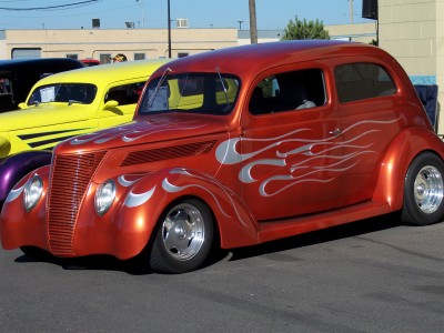 1972 Ford Ranchero - Orange hot rod with silver flame graphics is parked next to a yellow vehicle.
