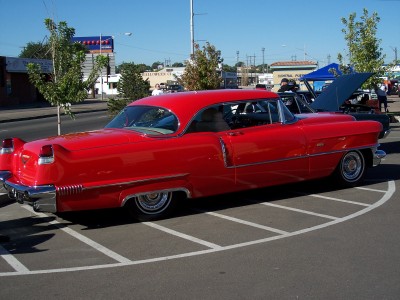1972 Ford Ranchero - A bright red classic Cadillac is parked in a lot on a sunny day.