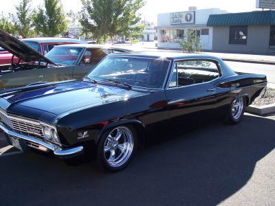 1972 Ford Ranchero - A black coupe with a shiny finish and chrome wheels is parked outside a building.