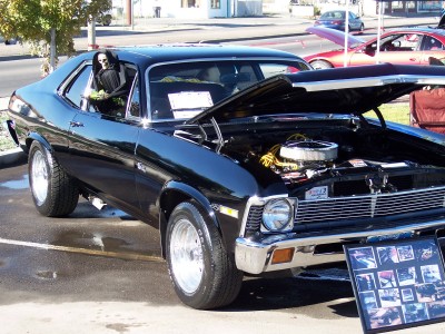 1972 Ford Ranchero - A black coupe, possibly a 1970 Nova, is on display with its hood open and a Grim Reaper figure seated inside.