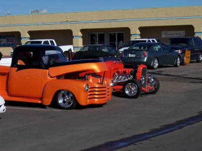 1972 Ford Ranchero - Two custom hot rod vehicles are parked in front of a building with other cars behind them.