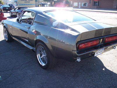 1972 Ford Ranchero - A classic muscle car with racing stripes is parked on an asphalt lot under a bright sun.