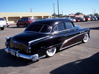 1972 Ford Ranchero - A black 1953 Buick Special sedan with whitewall tires is parked in a lot under a clear blue sky.