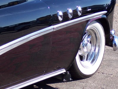 1972 Ford Ranchero - Close-up of a black car's side profile, chrome trim, fender vents, and classic whitewall tires.