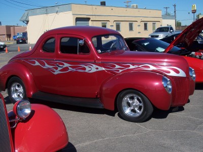 1972 Ford Ranchero - A classic red coupe with flame graphics is parked at an outdoor event with other vehicles present.