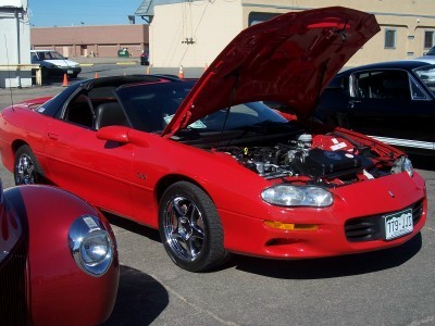 1972 Ford Ranchero - Red 1998 Chevrolet Camaro convertible on display with hood open. Another car is visible in the background.